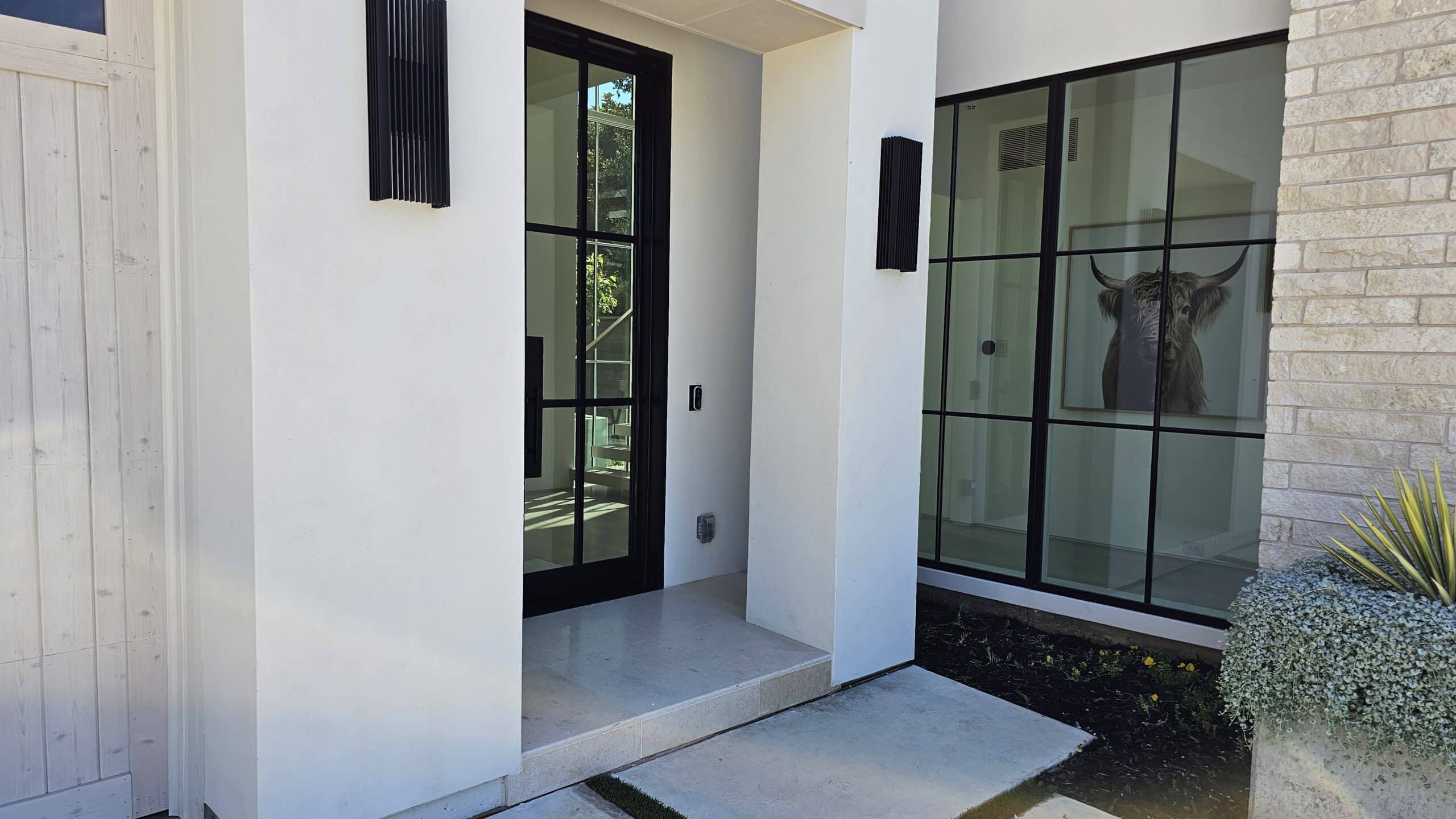 Modern entryway featuring a glass door and a full glass wall beside it
