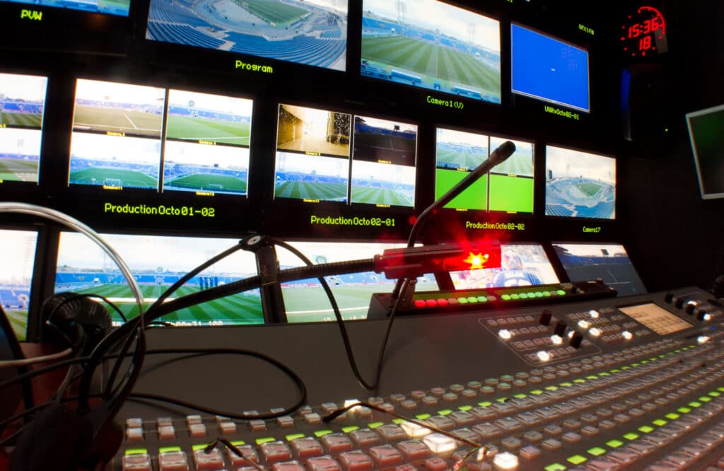 Broadcast control room with multi-camera feeds showing a live sports stadium.