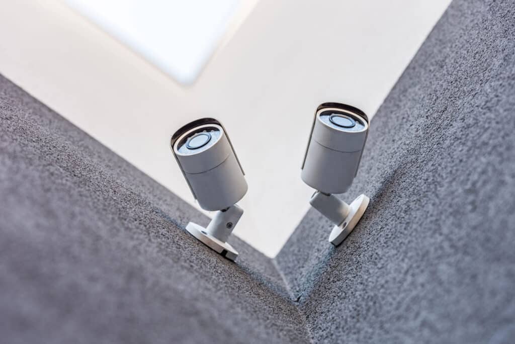 Two outdoor security cameras mounted on a building corner facing opposite directions.