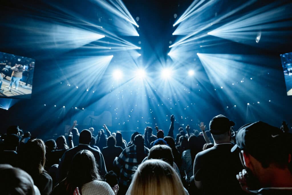 Concertgoers enjoying a live music show under dramatic blue stage lighting.