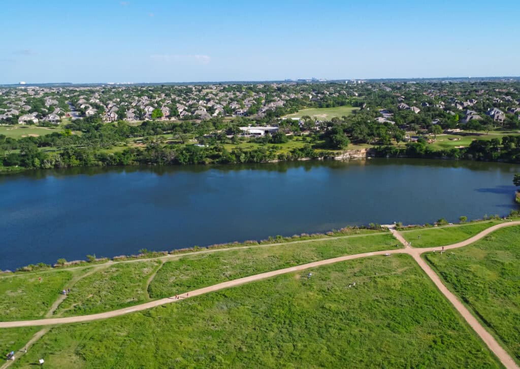 Aerial view of a lakeside trail with suburban homes in the background.