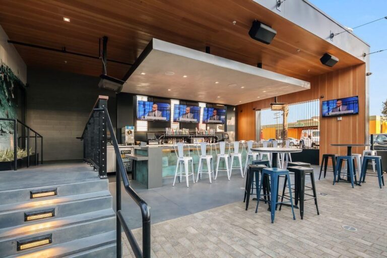 Outdoor bar with TVs, stools, and wood-paneled ceiling.
